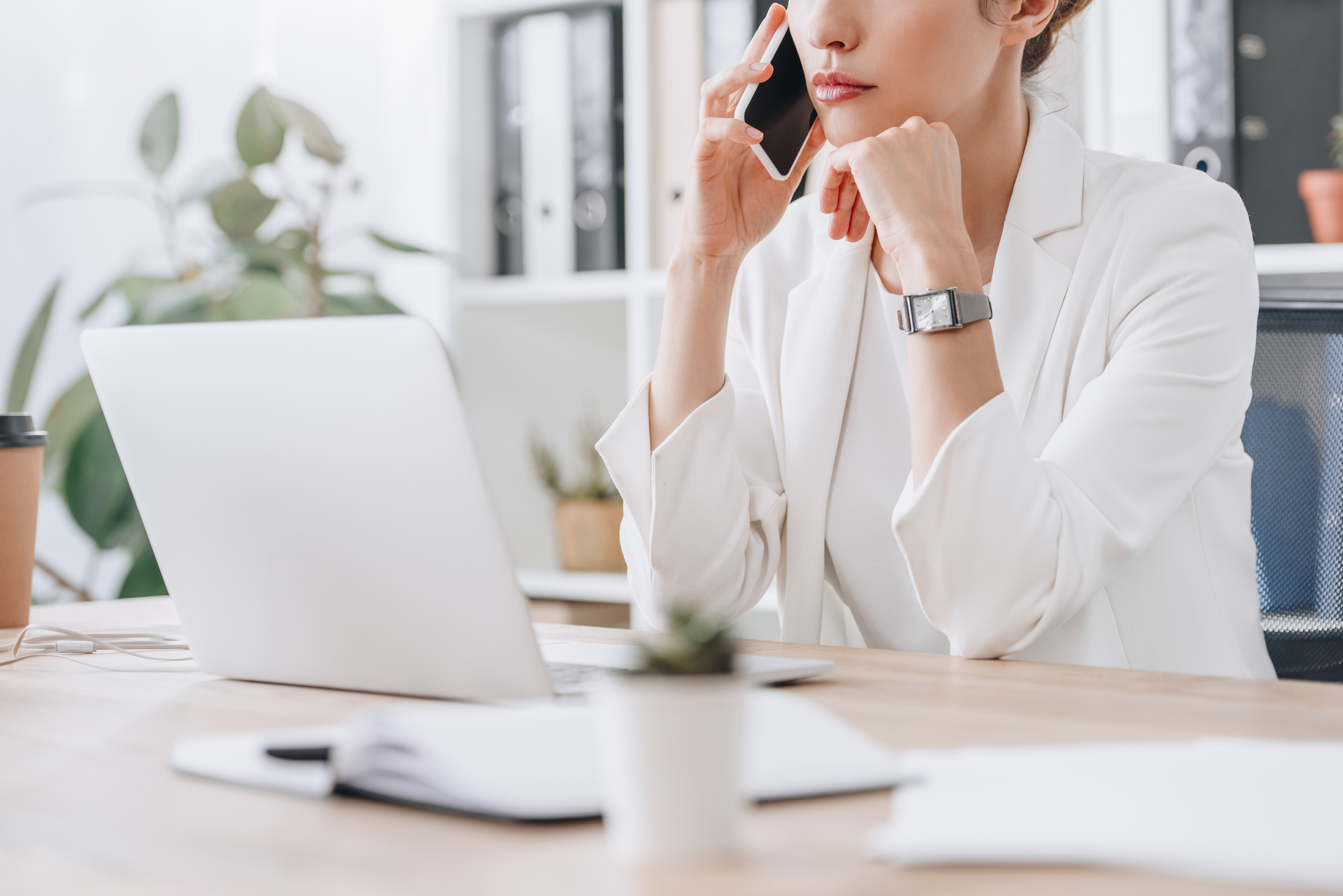 cropped view of frustrated businesswoman working with smartphone and laptop at workplace