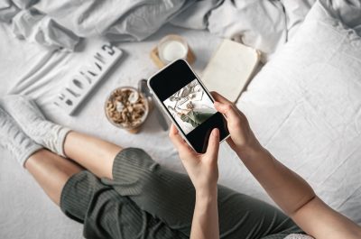 A woman takes a picture of her breakfast while lying in bed.